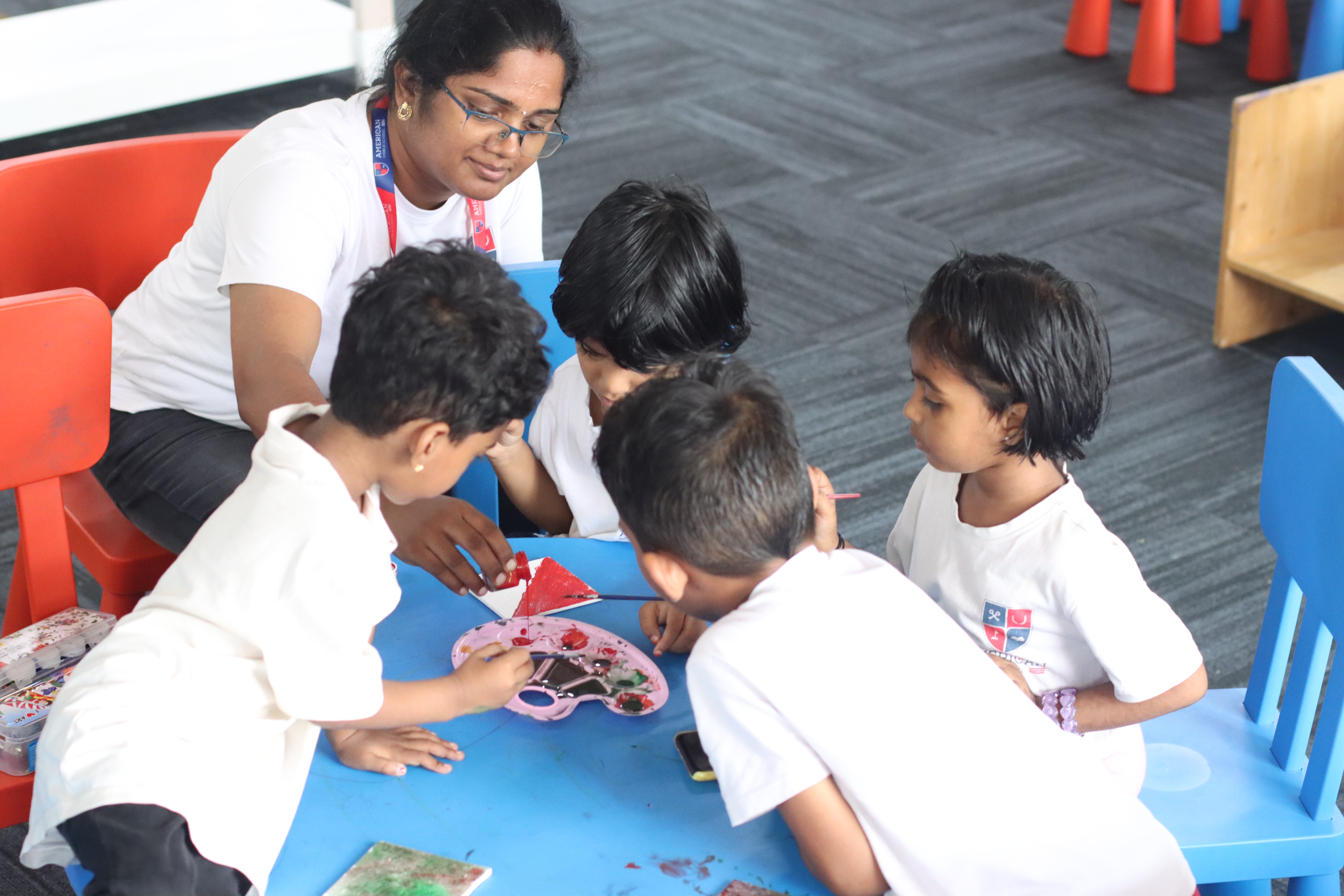 AWS Early Years teacher with four young children doing art at a play table