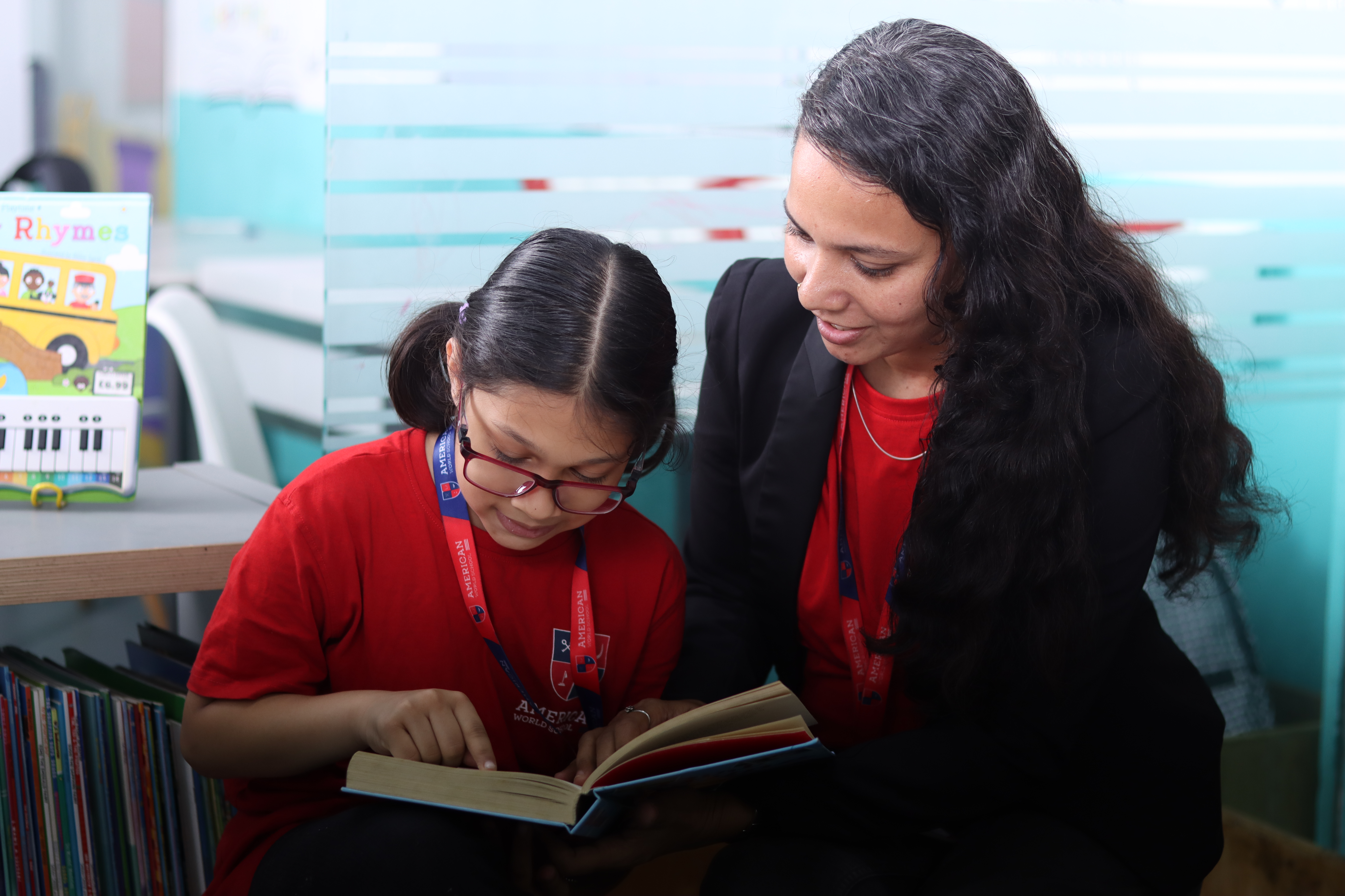 AWS teacher reading with a young student in a quiet library nook