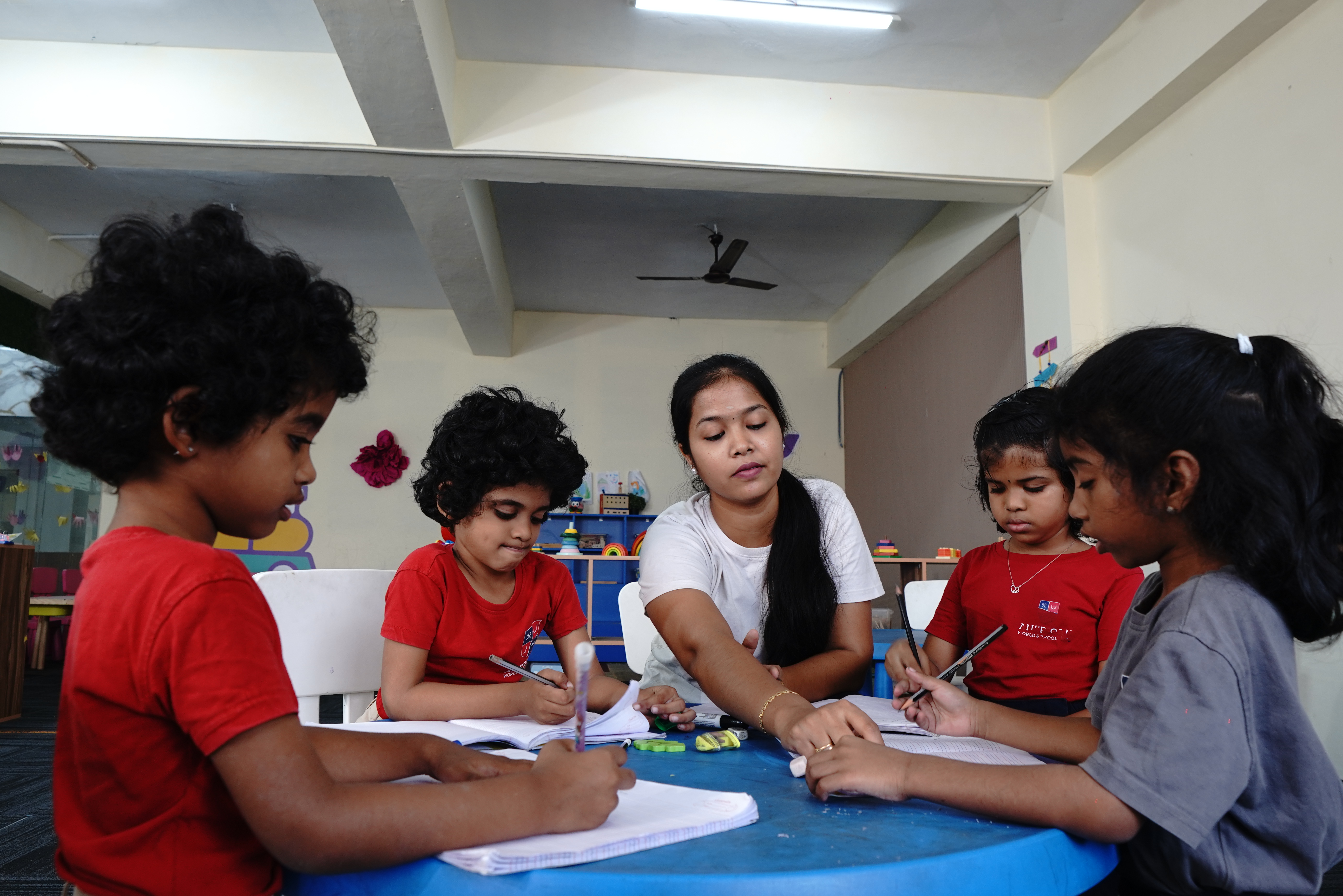 AWS Early Years teacher working with four children at a round table