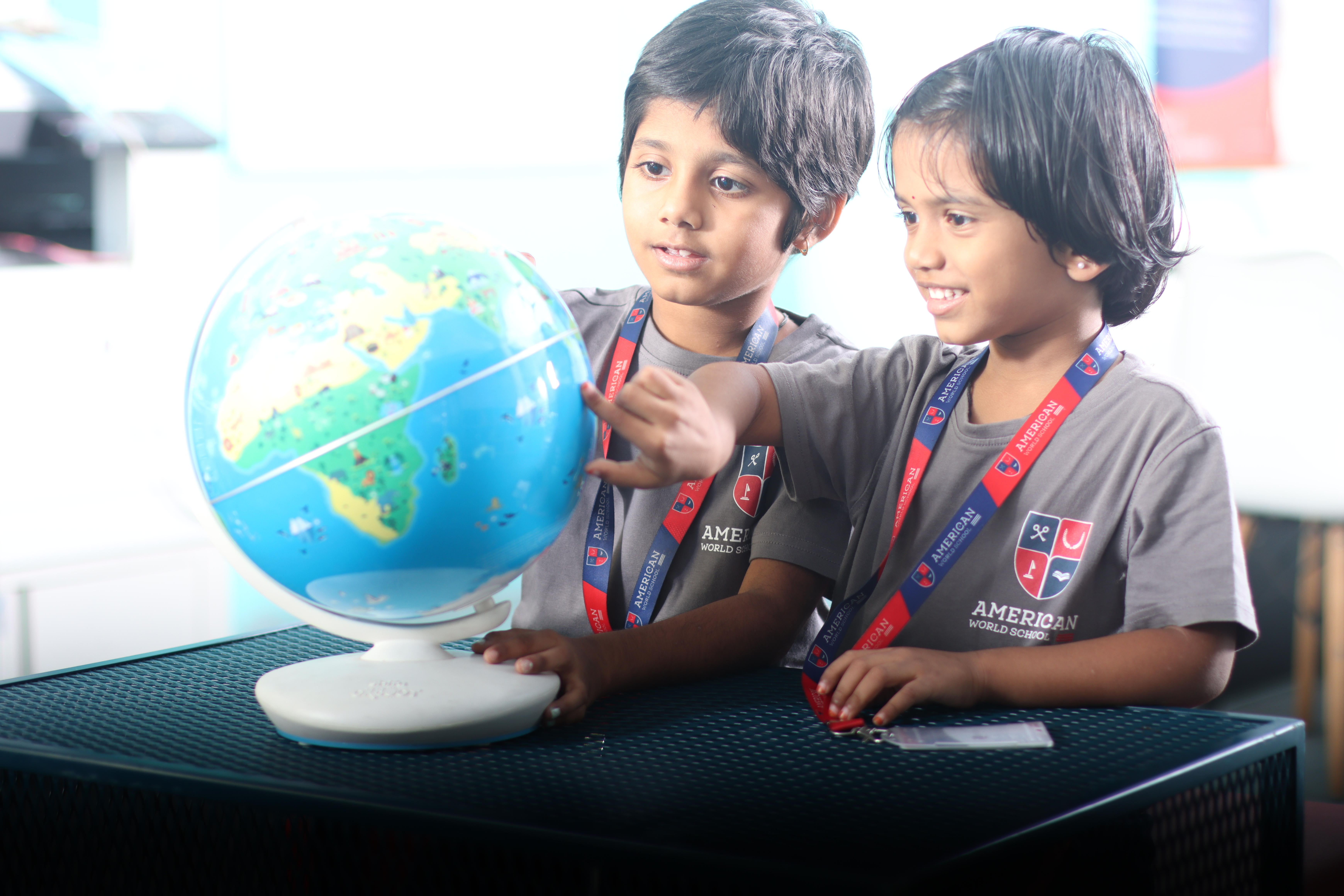 Young AWS students exploring a globe together