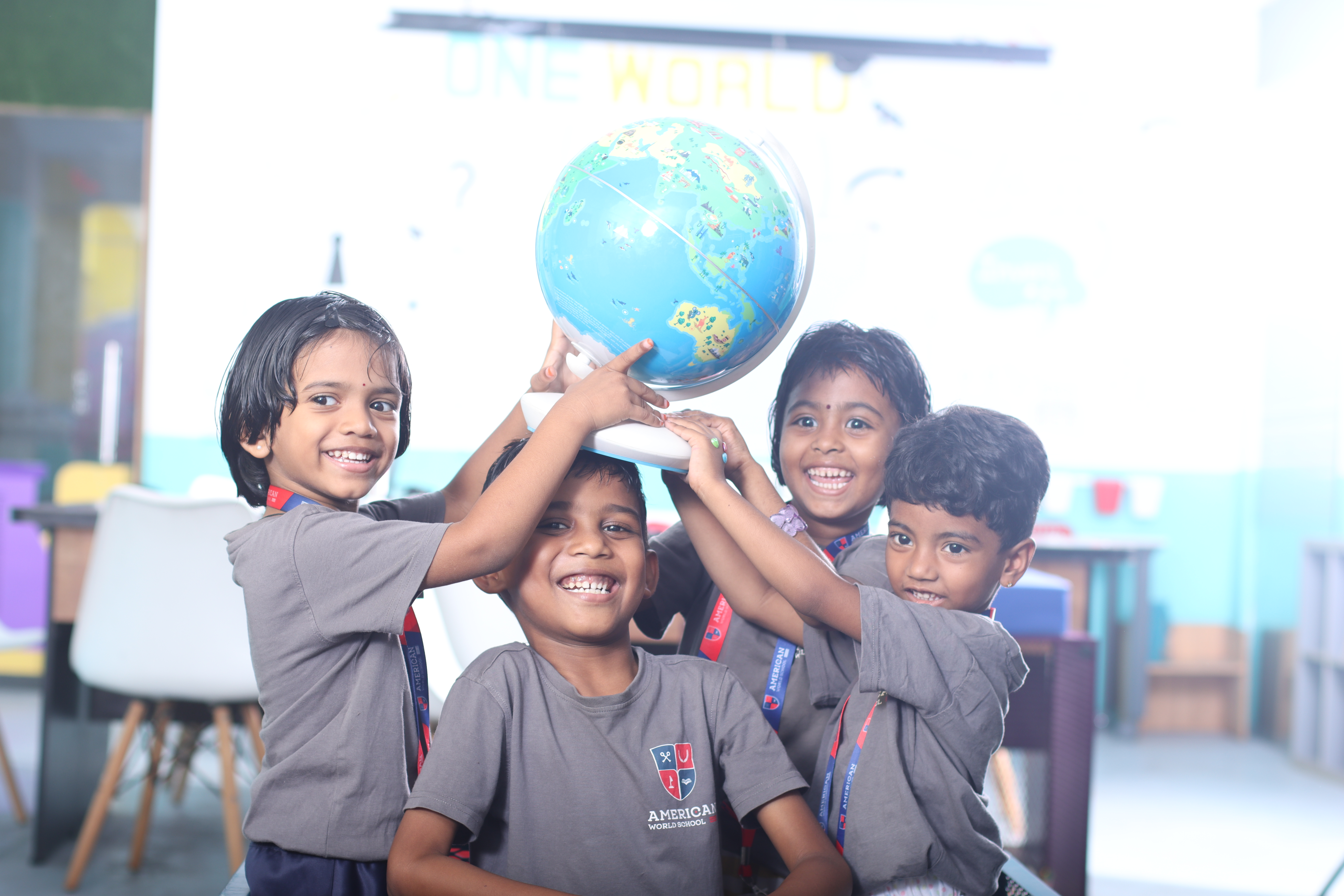 Young AWS students holding up a globe together under a One World banner