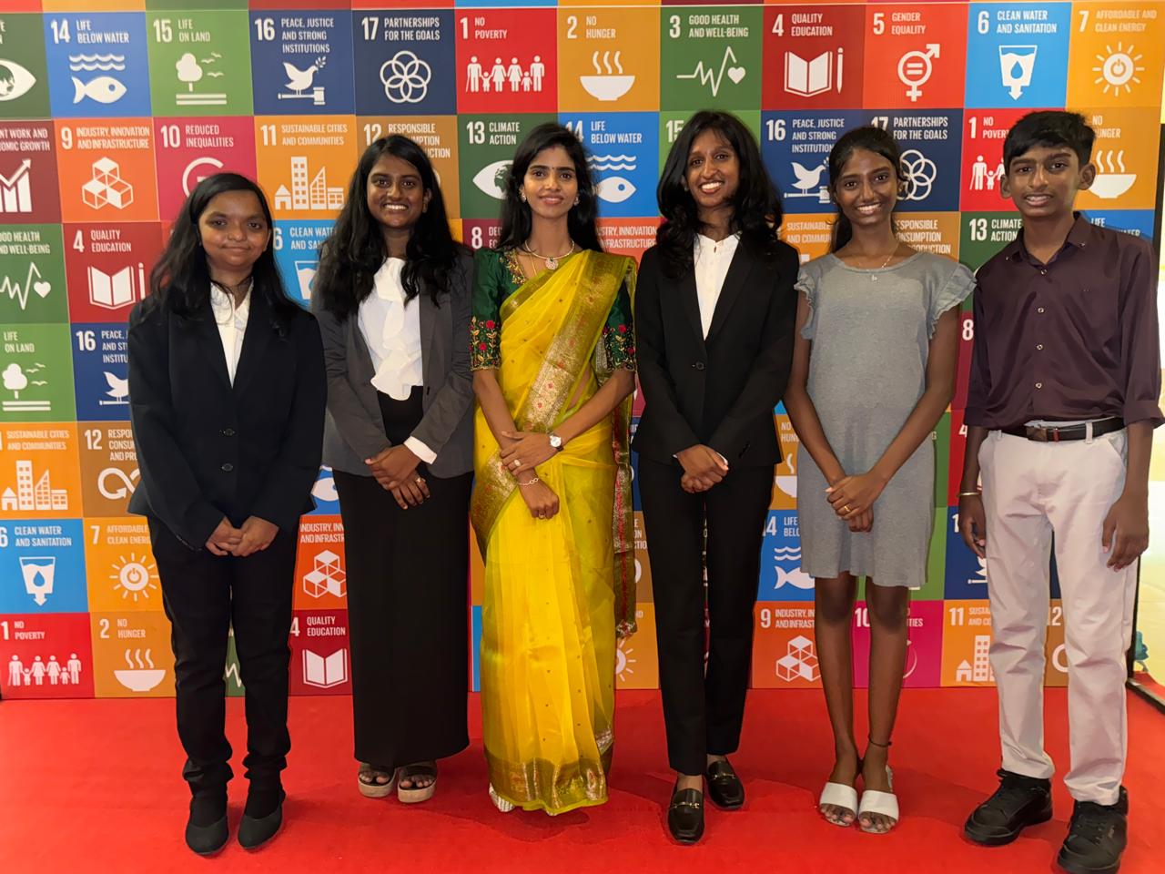 AWS students from diverse backgrounds standing before SDGs banner