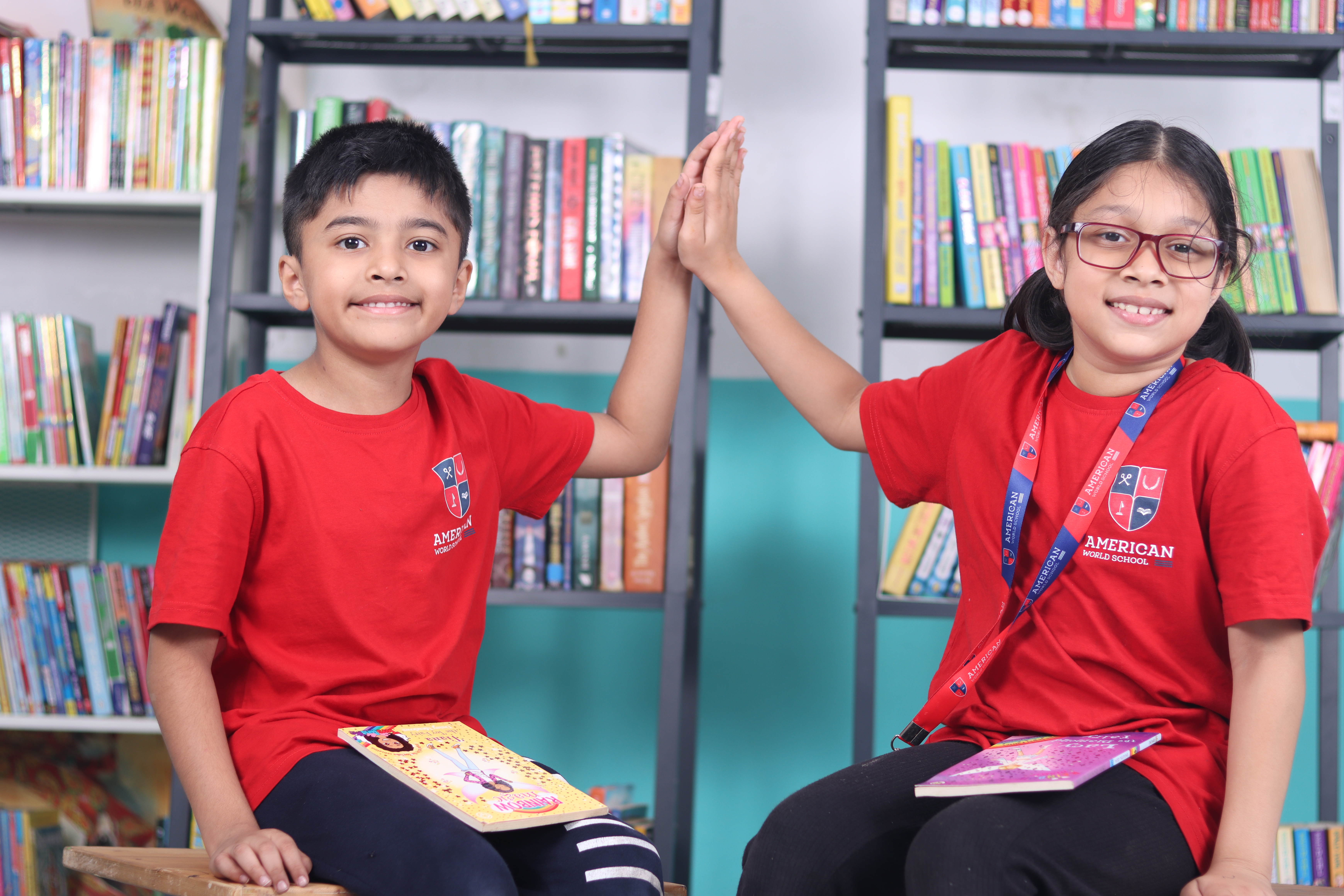 AWS lower elementary students high-fiving with their books