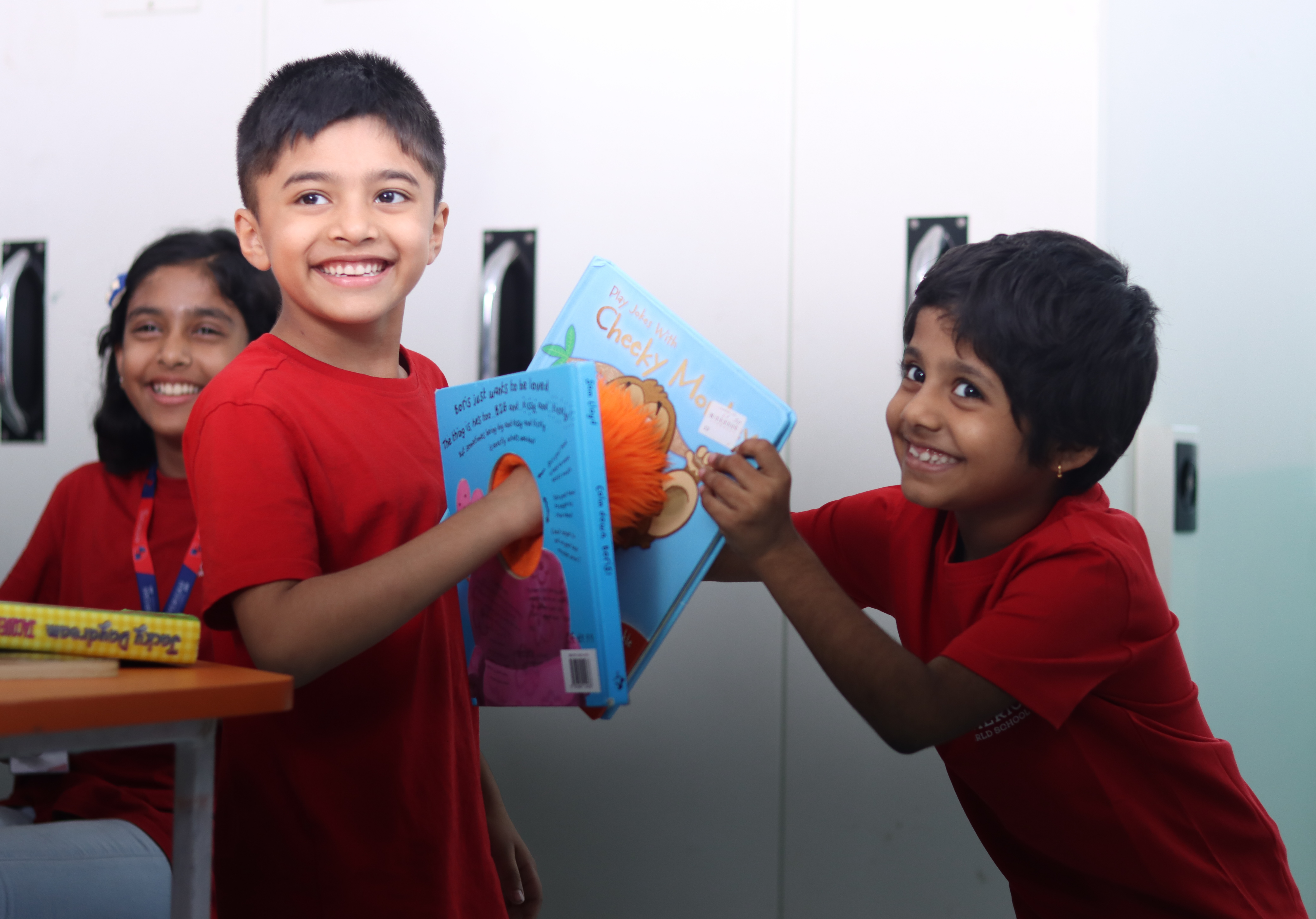 Two young AWS students laughing while reading a book together