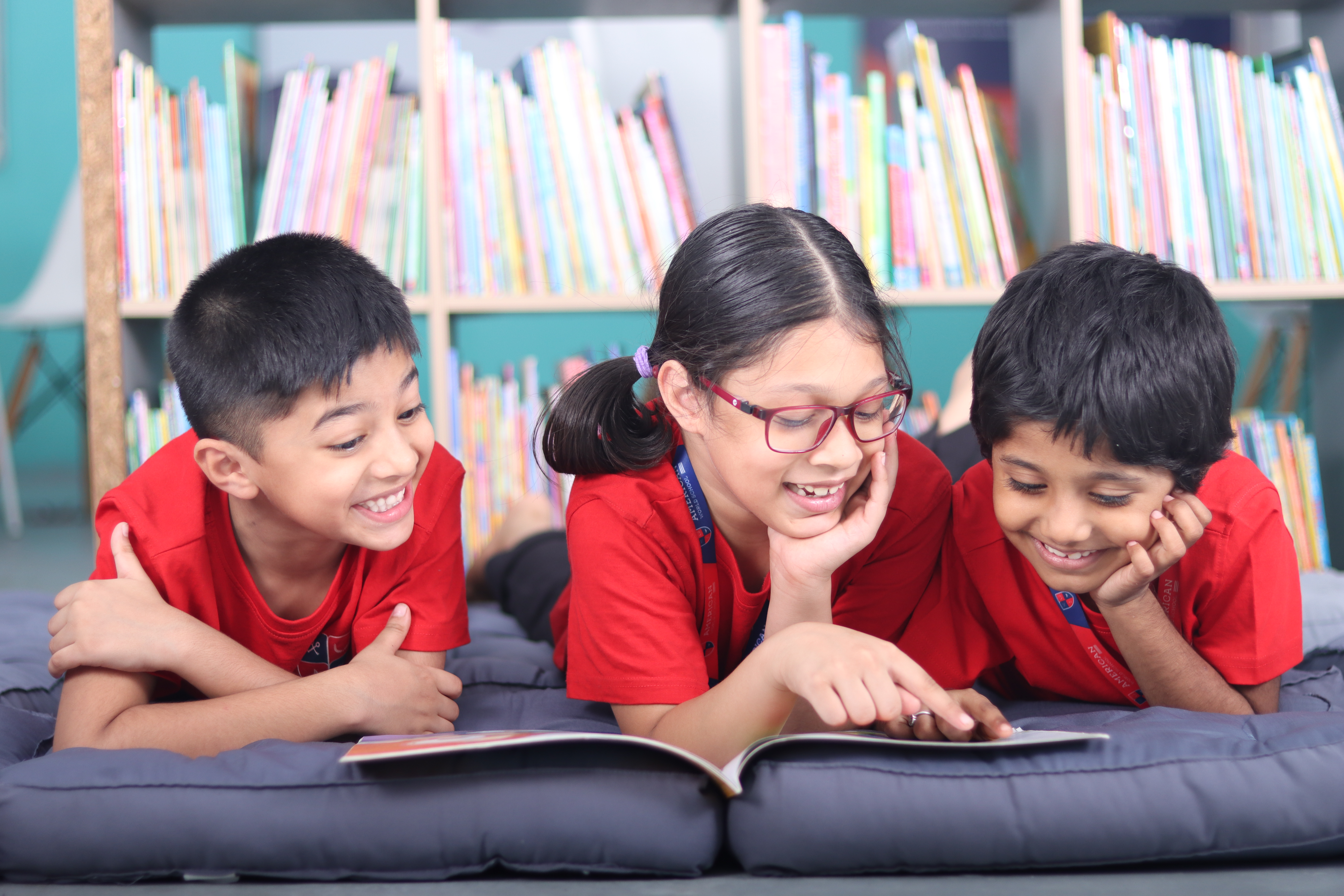 Three AWS lower elementary students lying on the floor reading together