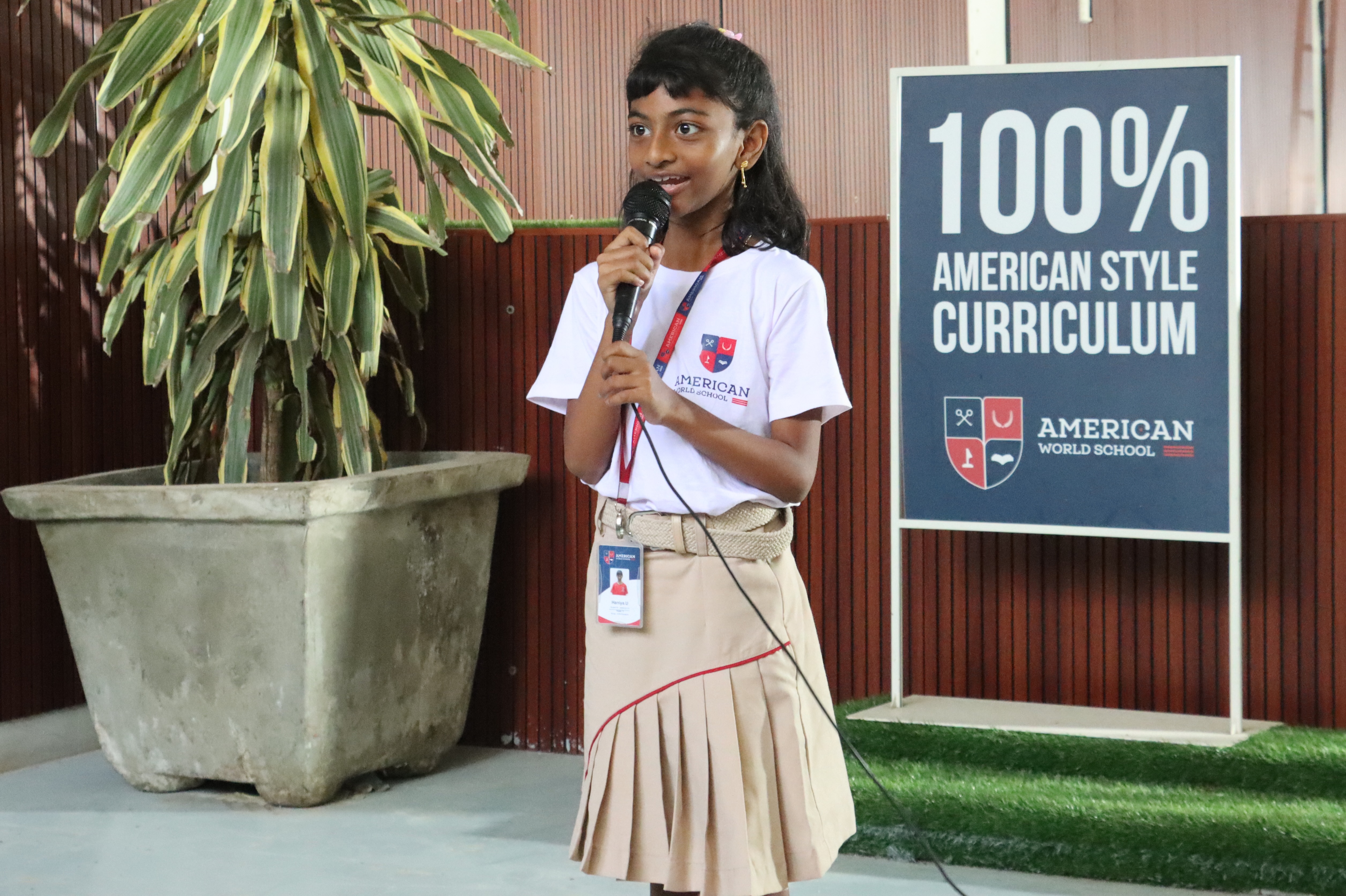 AWS student speaking under the 100% American Style Curriculum sign