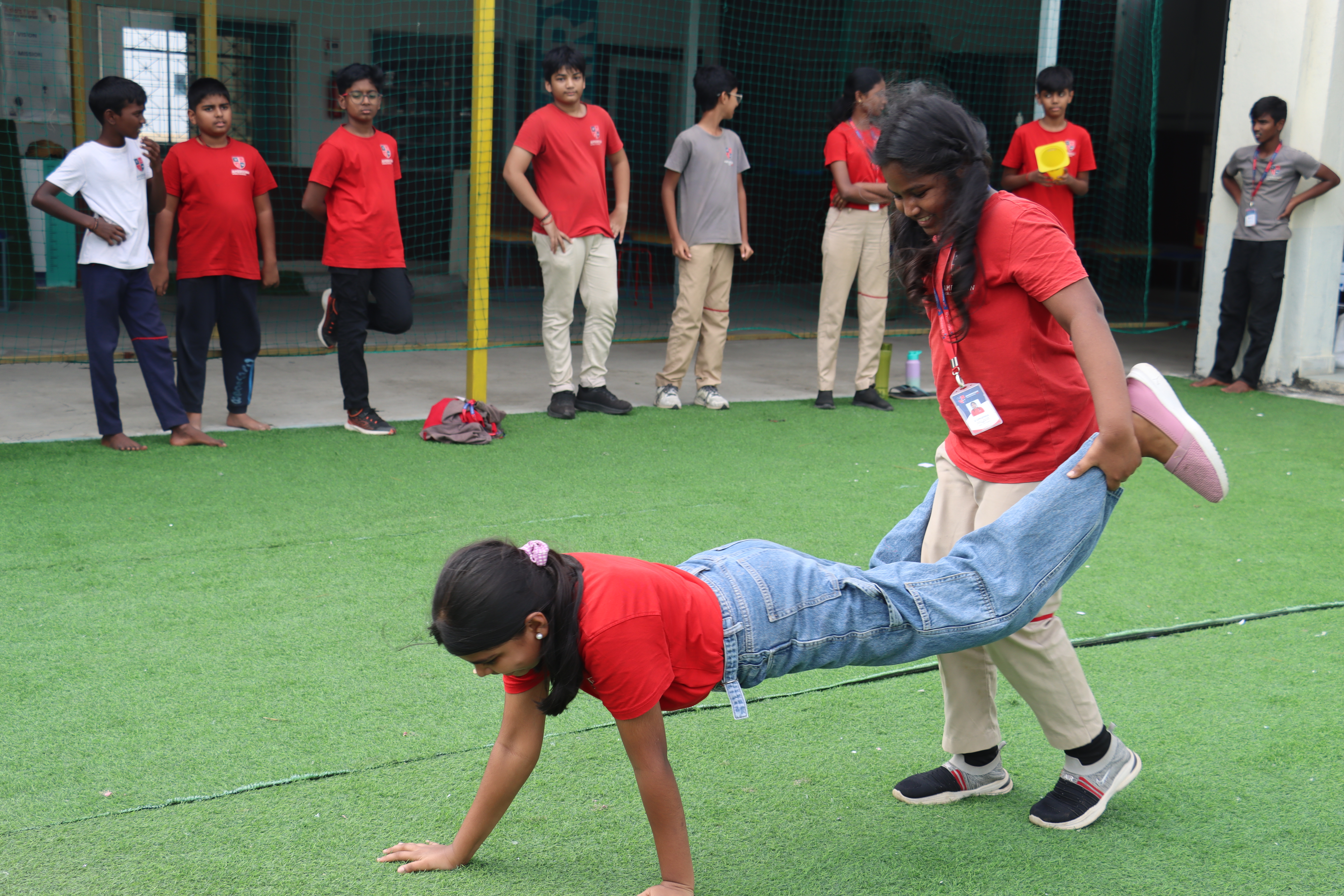 AWS student helping a younger one with floor exercises during PE